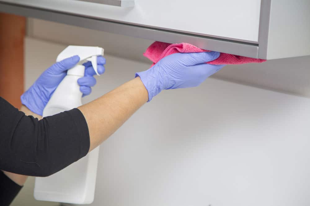 Bilde av en renholder som vasker en hylle på et legekontor eller en tannklinikk med en rosa mikrofiberklut - Midt-Norsk Vask AS - Fasadevask